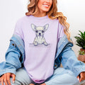 May include: A light purple t-shirt featuring a detailed illustration of a Chihuahua dog. The dog is depicted in a realistic style, with its paws resting on a wooden ledge. The shirt is a solid color, and the dog illustration is the focal point.
