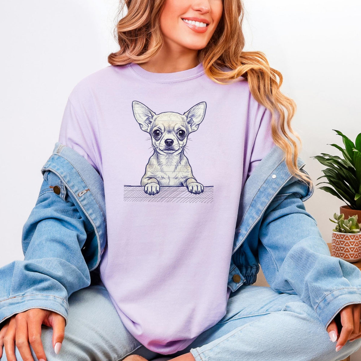 May include: A light purple t-shirt featuring a detailed illustration of a Chihuahua dog. The dog is depicted in a realistic style, with its paws resting on a wooden ledge. The shirt is a solid color, and the dog illustration is the focal point.